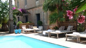 A poolside area with lounge chairs and a pool. - Villa Station Las Salinas (Ses Salines)