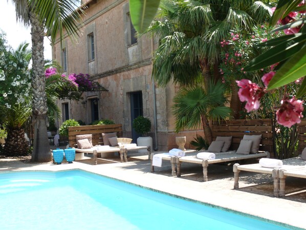 Una piscina al aire libre, sombrillas, tumbonas