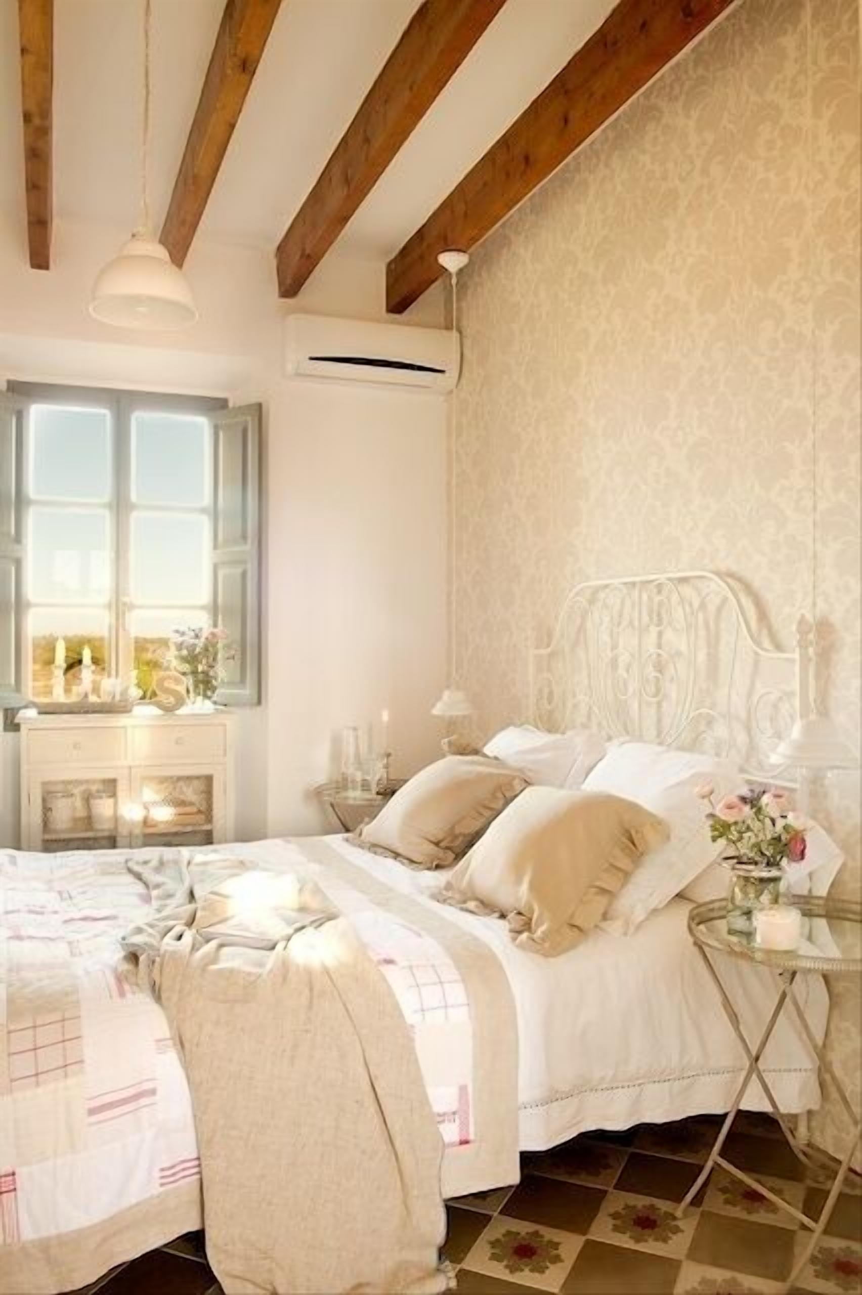 A bedroom with a bed, bedside tables, a window, and a hanging light fixture.