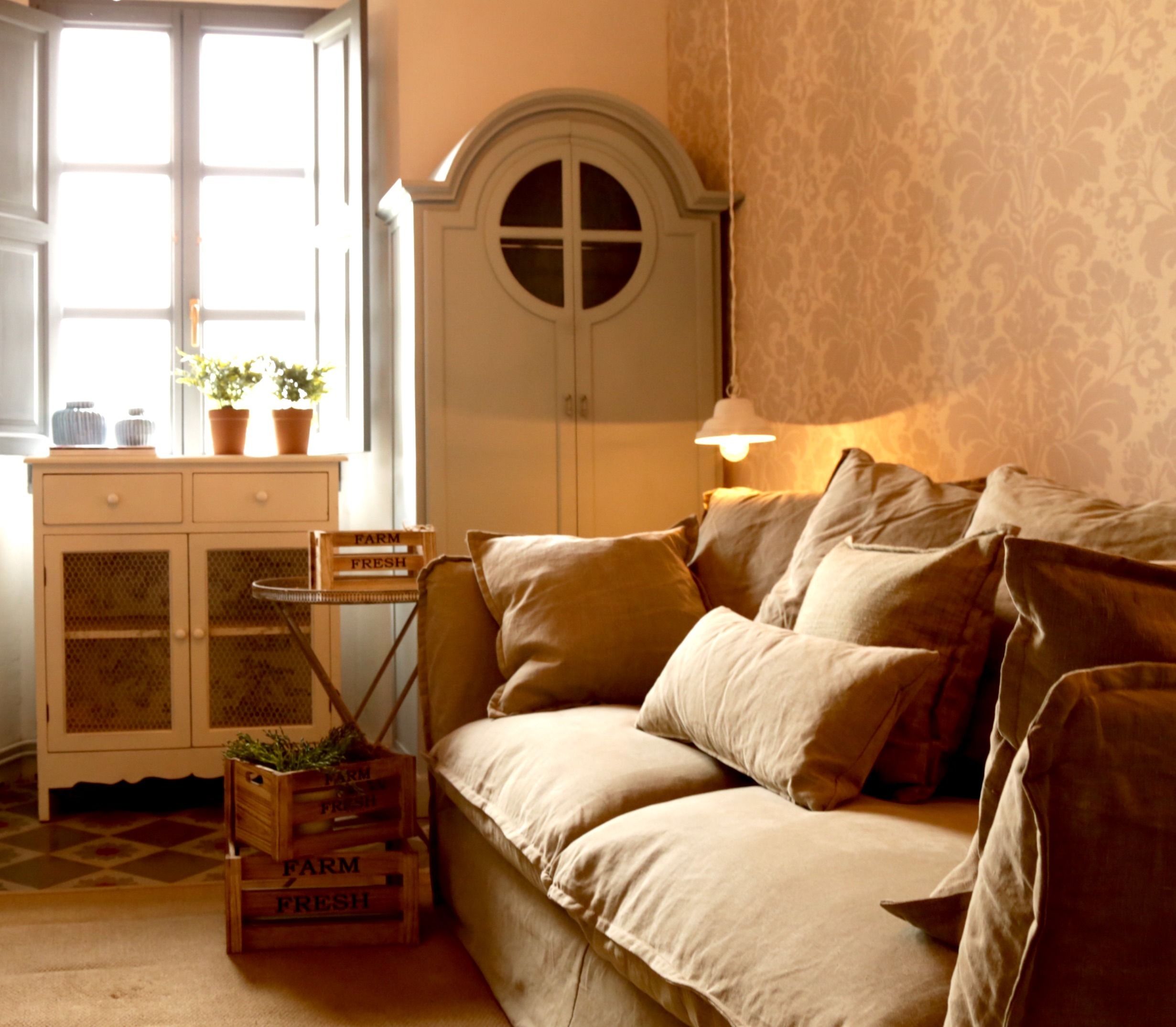 Una habitación acogedora con un sofá, un aparador con puertas de vidrio y una lámpara.