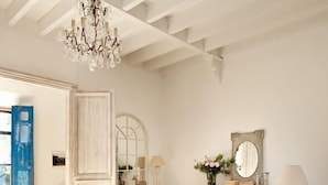 A living room with a white sofa, a coffee table, a chandelier, and a mirror on the wall. - Villa Station Las Salinas (Ses Salines)