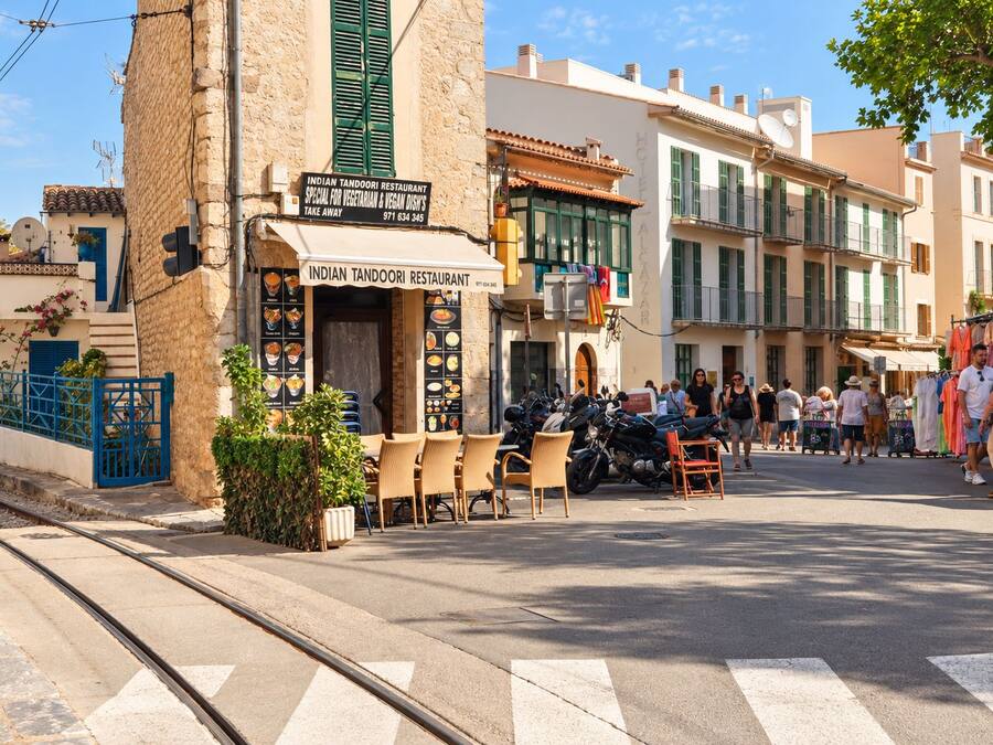 Vista de la calle con un restaurante llamado 'Indian Tandoori Restaurant' que ofrece opciones vegetarianas y veganas.