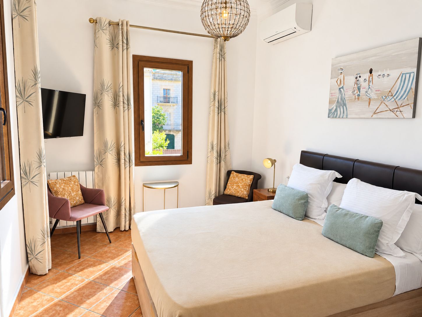 Une chambre d’hôtel avec un grand lit, une télévision, une petite table, une chaise et un tableau au mur.