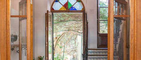 A wooden-framed doorway leading to a tiled patio with a staircase and a stained glass window.
