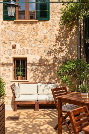 A stone building with a wooden bench and table, surrounded by potted plants. - Hotel Casa Bougainvillea (Sóller)