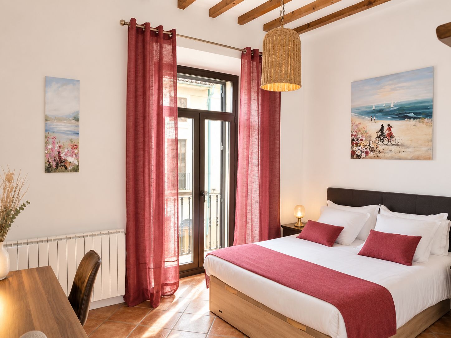 A bedroom with a bed, curtains, a hanging light, and two paintings on the walls.