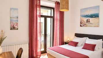 A bedroom with a bed, curtains, a hanging light, and two paintings on the walls.
