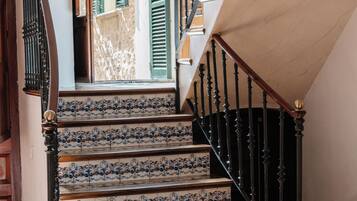 A staircase with blue and white patterned tiles, a wooden handrail, and a black iron railing.