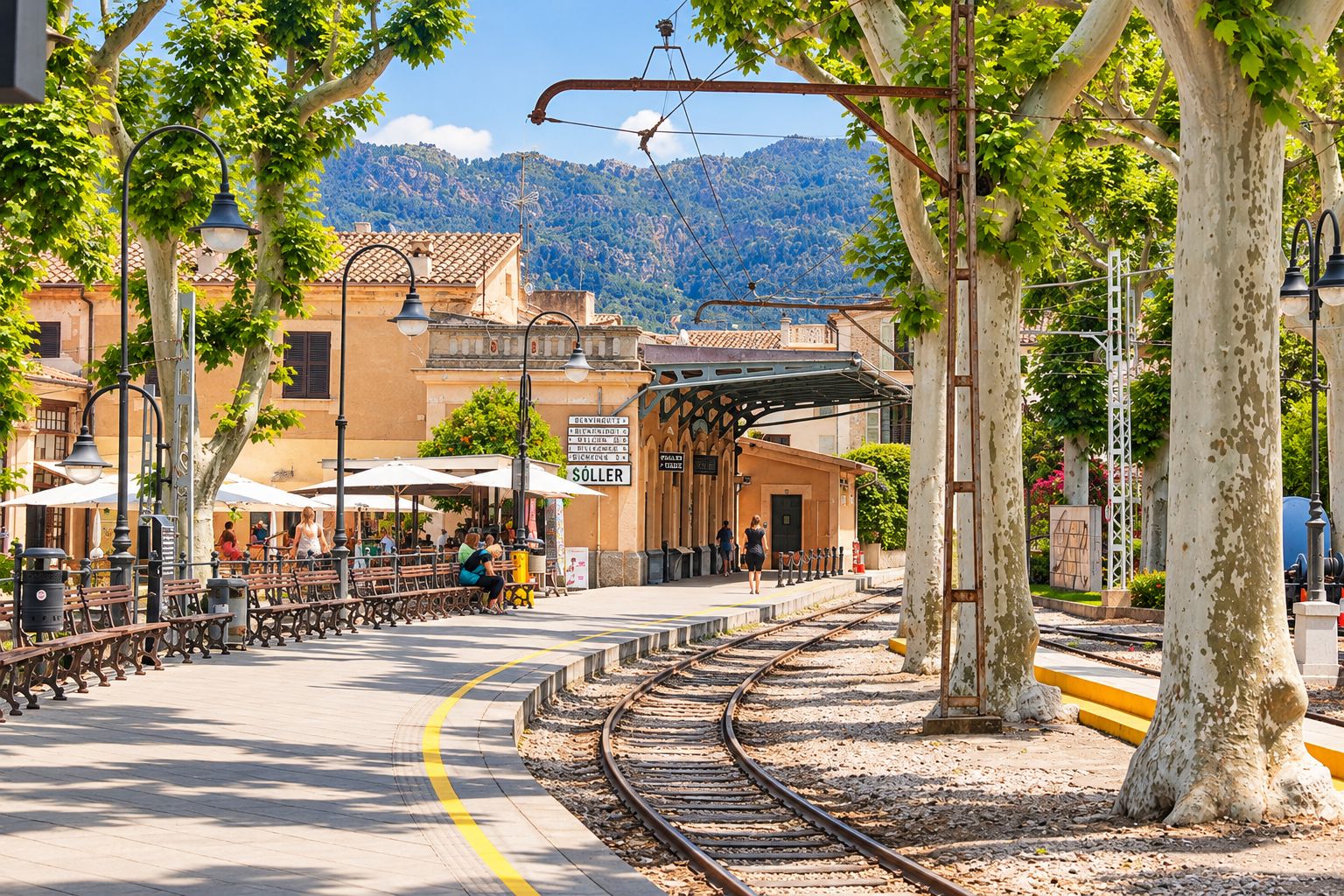 A train station platform with benches, a covered waiting area, and a clear view of the tracks.