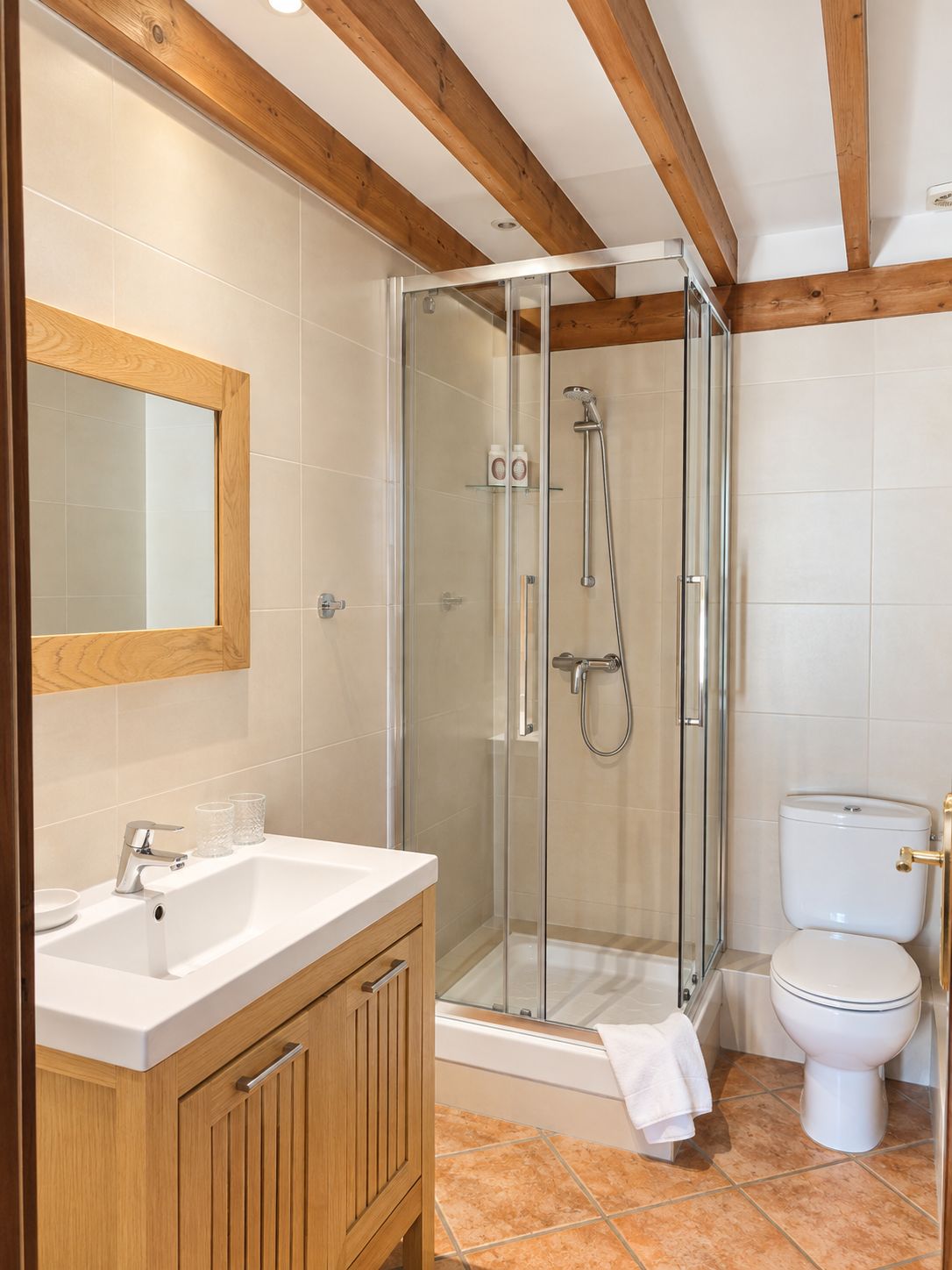 A bathroom with a glass-enclosed shower, a white sink, and a toilet.