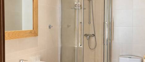 A bathroom with a glass-enclosed shower, a white sink, and a toilet.