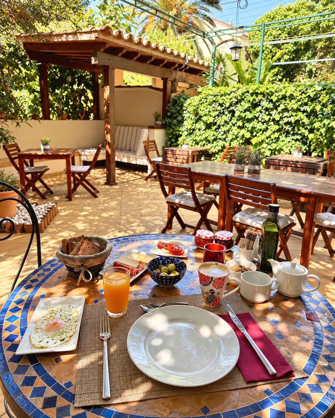 An outdoor dining area with a mosaic table, chairs, and a variety of food and drink items.