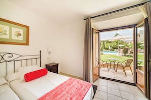 A hotel room with a bed, a small table, and a view of an outdoor pool area. - Ca'l Bisbe (Sóller)