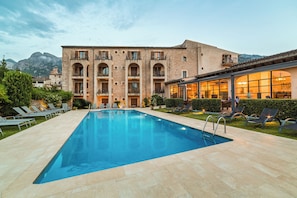 A swimming pool with lounge chairs and a building with multiple balconies. - Ca'l Bisbe (Sóller)