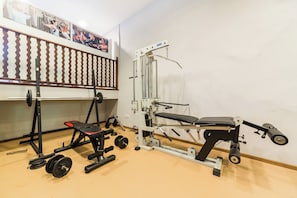 A gym with various exercise equipment including a bench press, squat rack, and weight plates. - Ca'l Bisbe (Sóller)