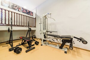 A gym with various exercise equipment including a bench press, squat rack, and weight plates.