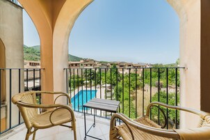 Ein Balkon mit Korbmöbeln, ein Pool und Blick auf eine Wohngegend.