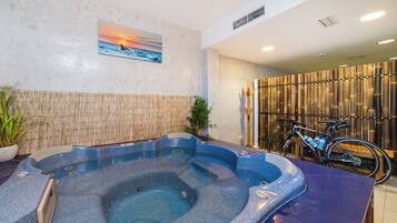 Un espacio de spa con un jacuzzi, una pared de bambú y una bicicleta.