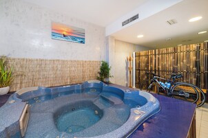 Área de spa com hidromassagem, parede de bambu e bicicleta.