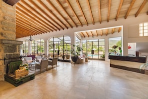 Eine geräumige Lobby mit Kamin aus Stein, großen Fenstern und Holzboden.