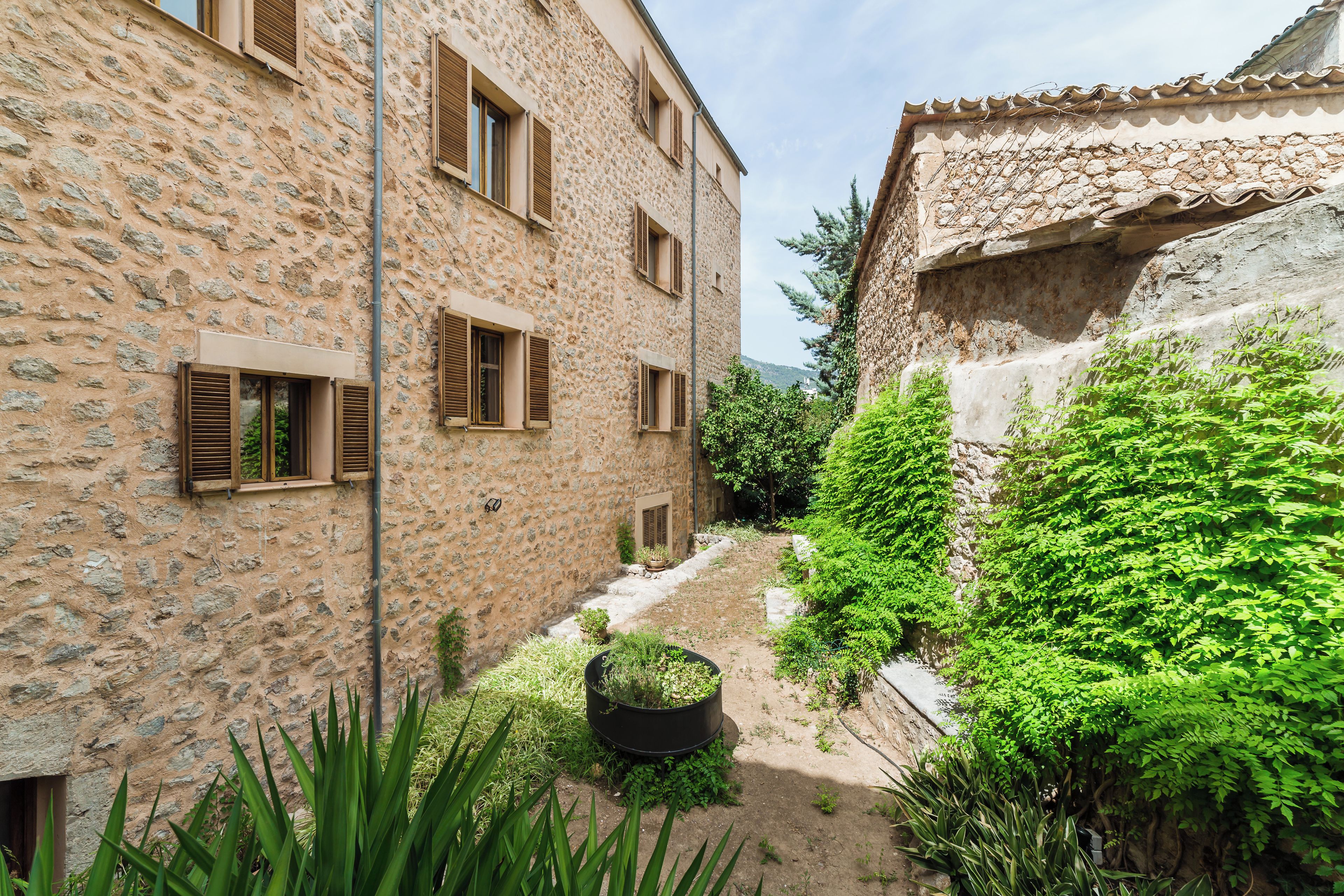 A stone building with multiple windows and a narrow alleyway.