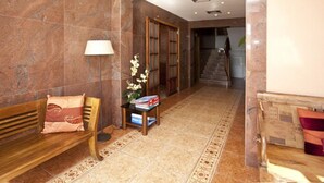 A lobby with a wooden bench, a standing lamp, a small table with books, and a staircase in the background. - Hotel Ses Figueres (Ibiza Town)