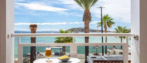 A balcony with a table, a bowl of fries, and a glass of beer.