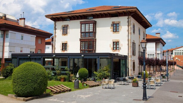 A hotel with a traditional facade, large windows, and outdoor seating area. - La Casa del Patrón (Zuia)