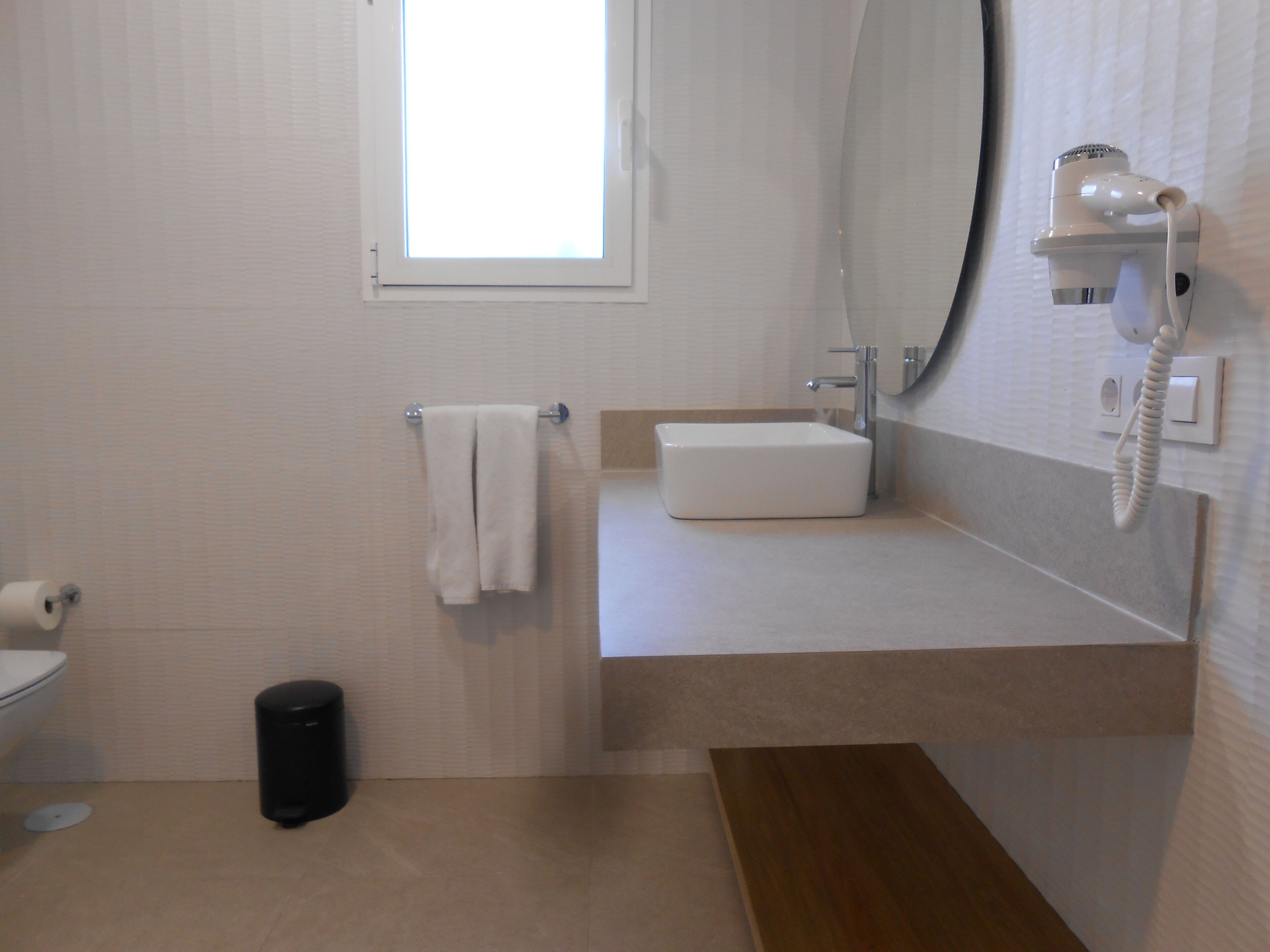 A bathroom with a toilet, a sink, a mirror, and a towel rack.