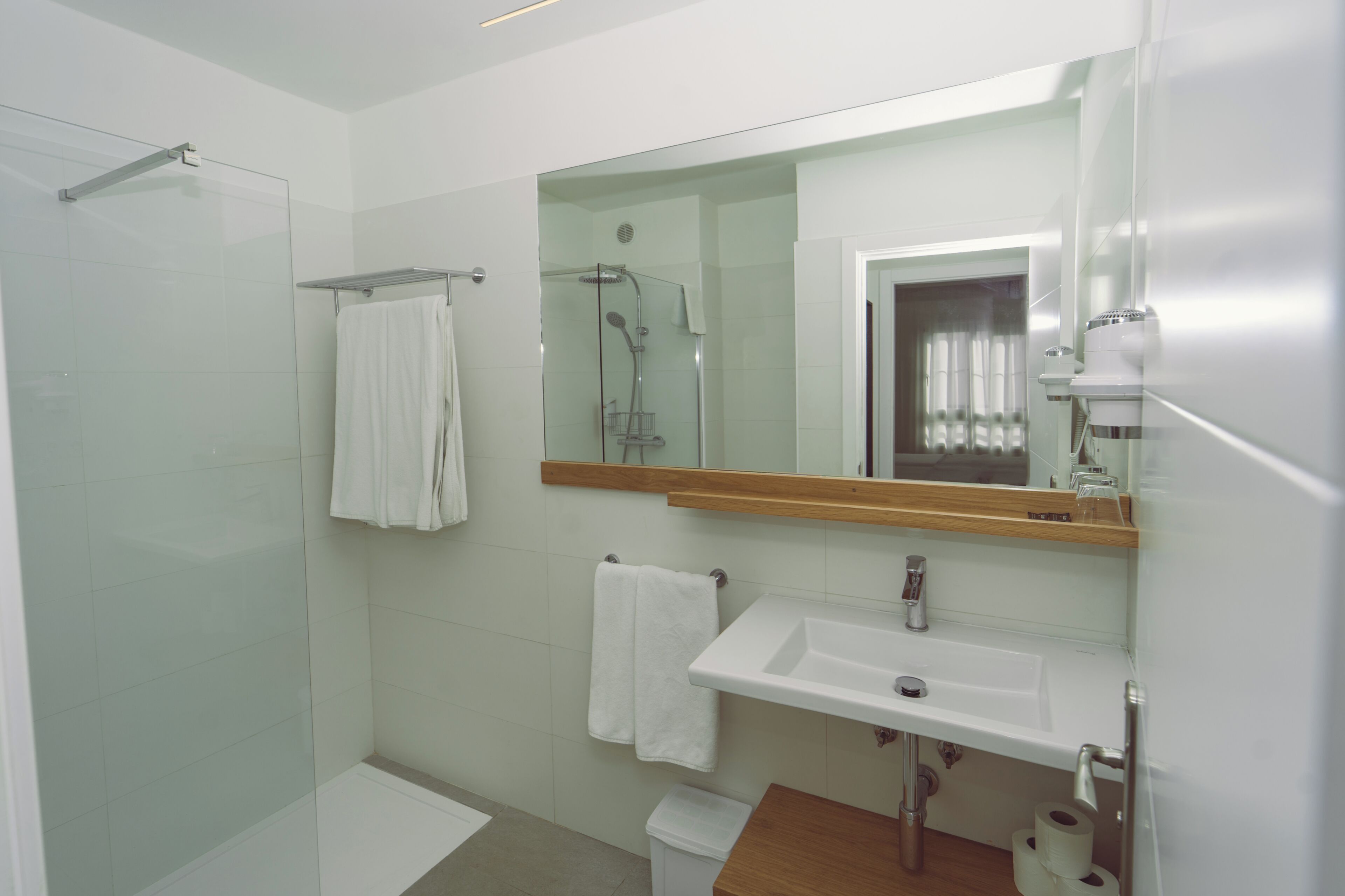A modern bathroom with a glass shower enclosure, a white sink, and a large mirror.