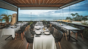 Een terras met tafels voor twee personen, met uitzicht op zee.