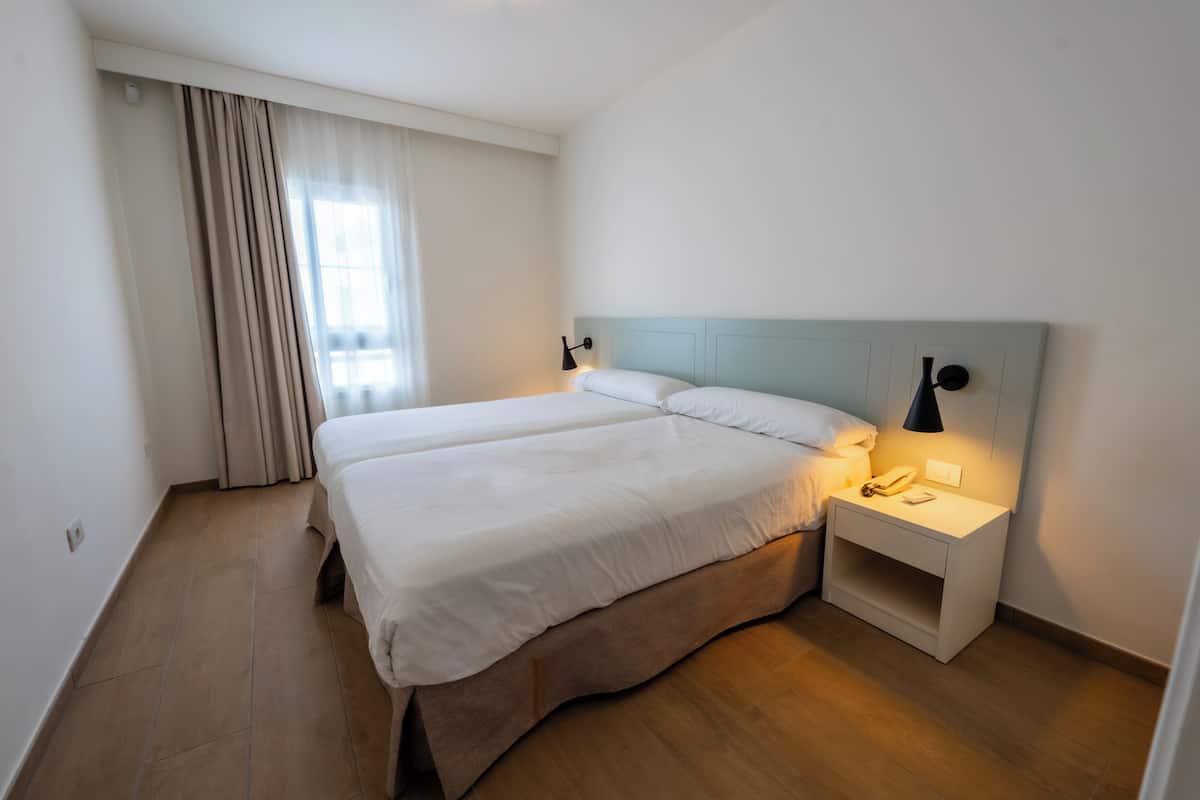 A hotel room with a bed, bedside lamp, and a nightstand.