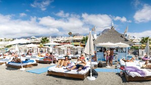 Een strand met ligbedden en parasols.