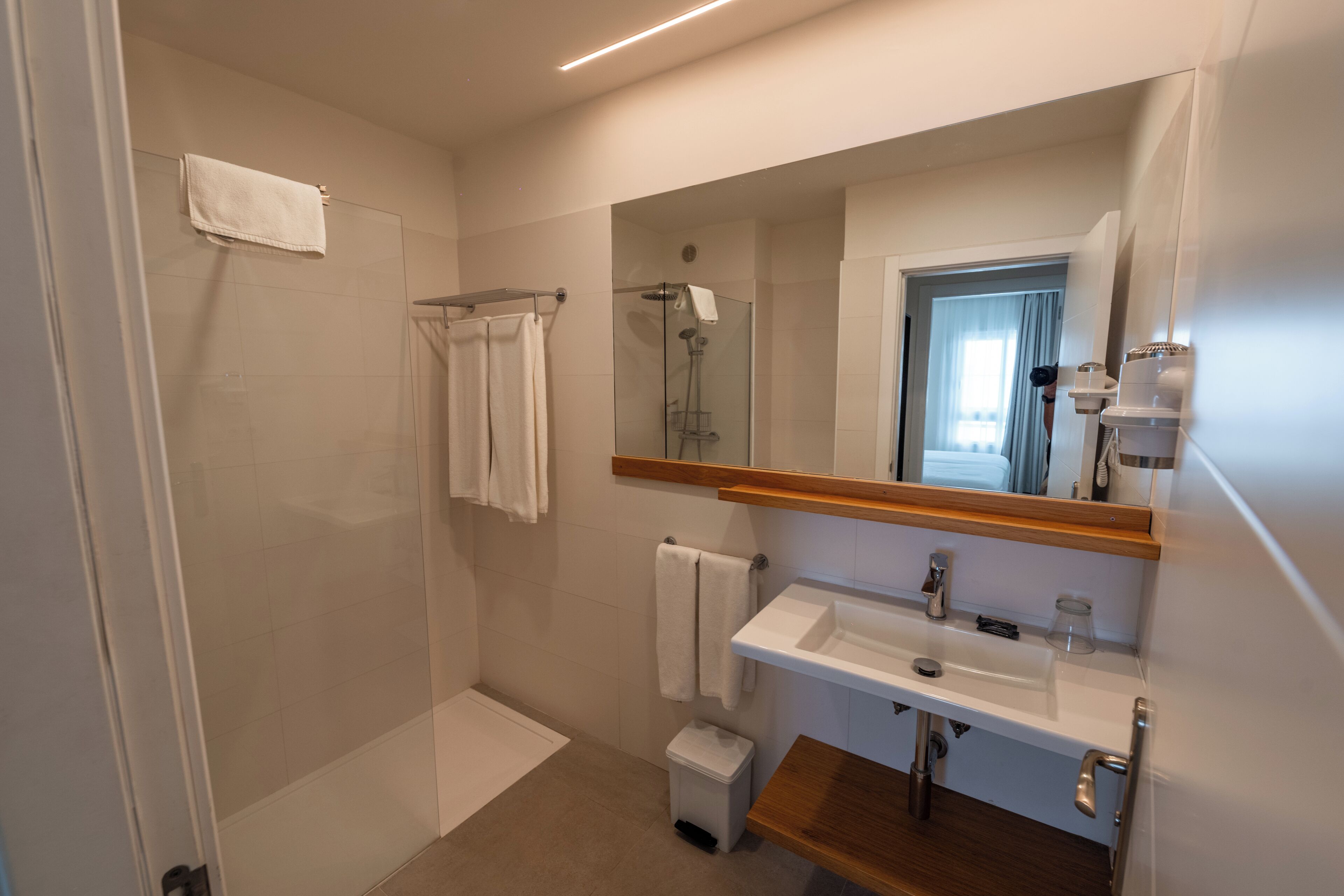 Un baño moderno con cabina de ducha de vidrio, lavamanos y espejo.