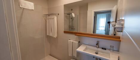 Un baño moderno con cabina de ducha de vidrio, lavamanos y espejo.