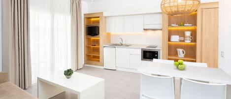 A modern kitchen with white cabinets, a dining area with a white table and chairs, and a ceiling fan.