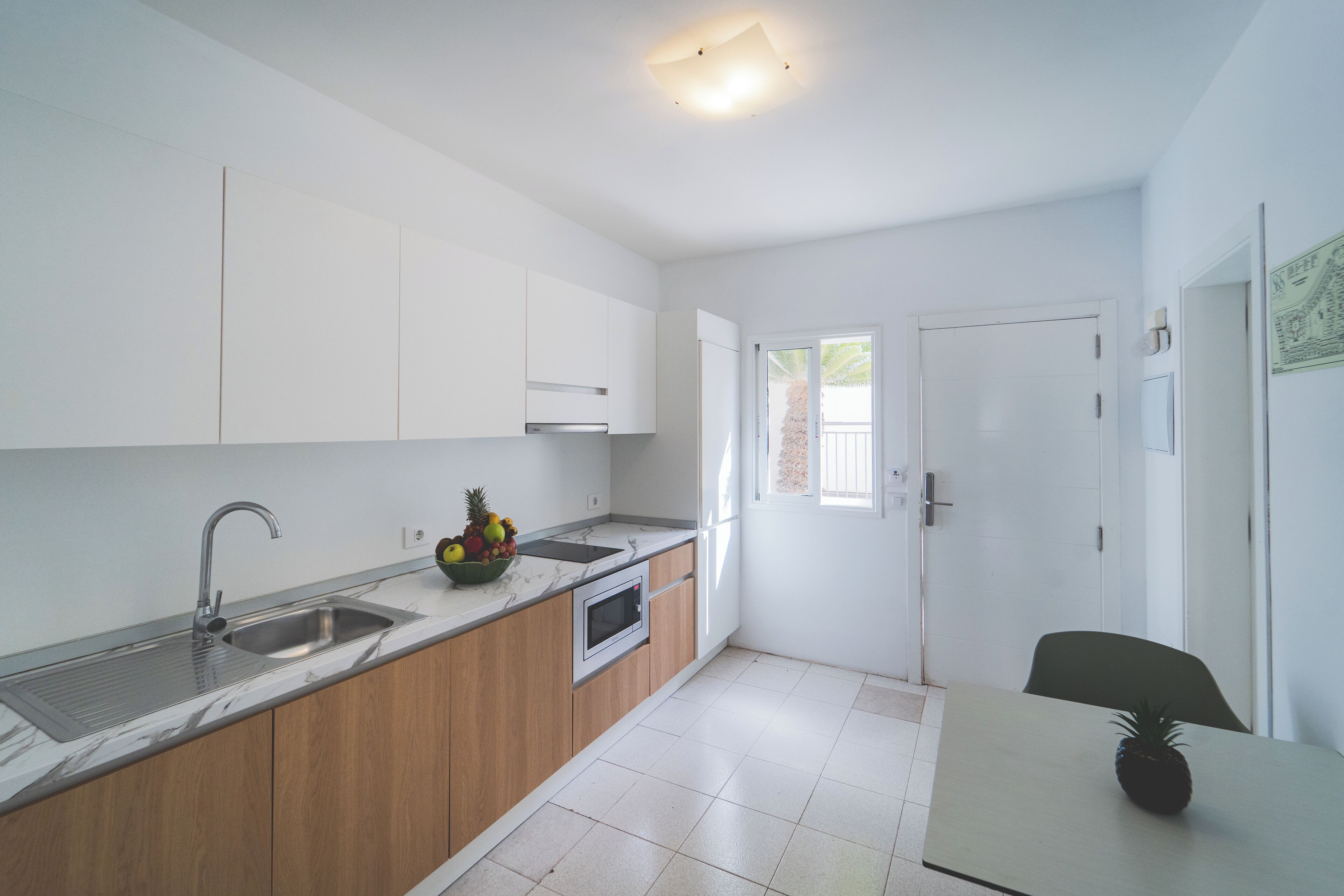 Una cocina moderna con un lavamanos, microondas y armarios de madera.