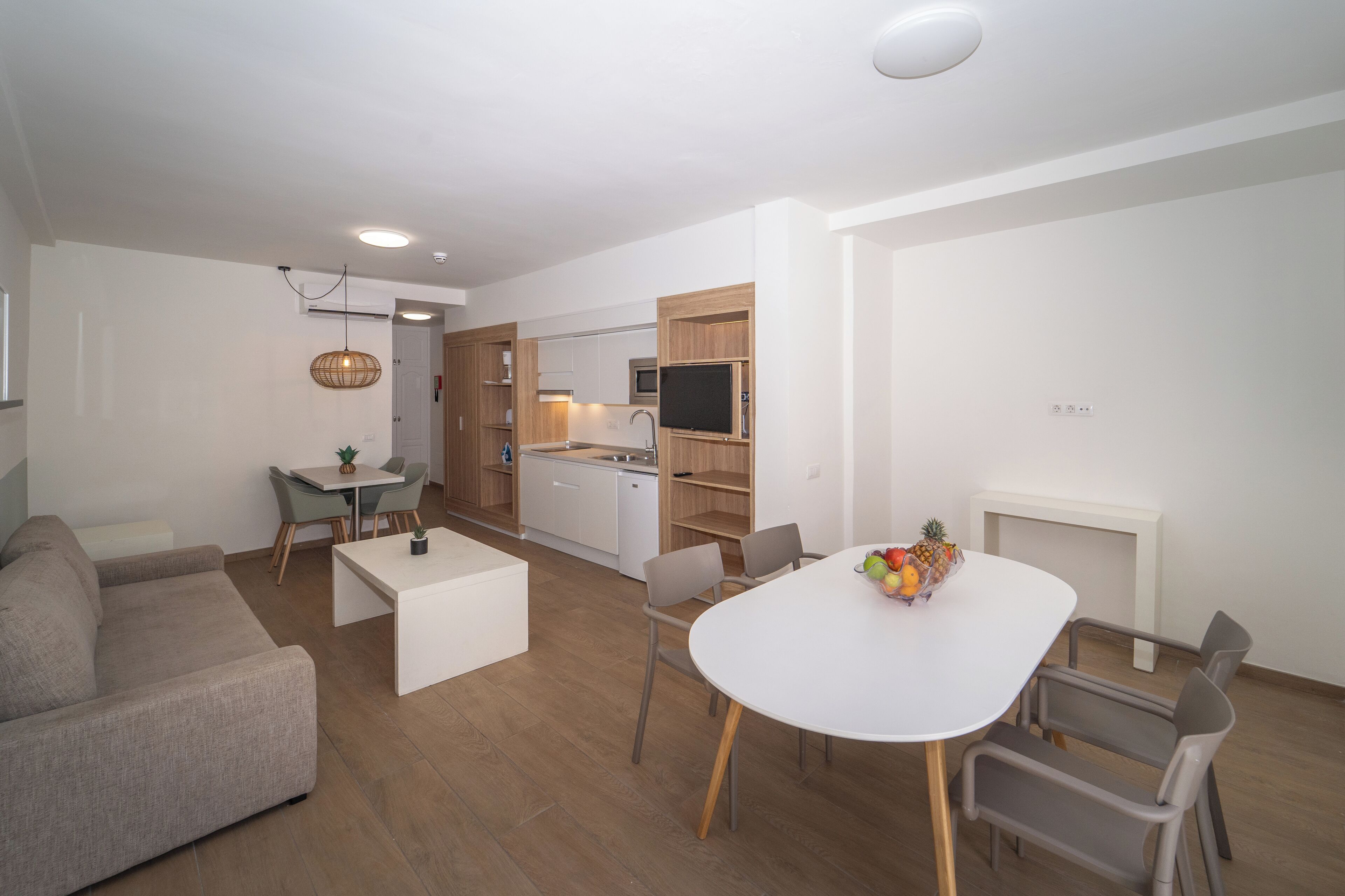 Uma sala de estar moderna com sofá, mesa de jantar com cadeiras, cozinha com micro-ondas e lareira.