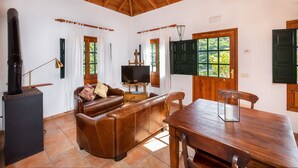 A living room with a wooden ceiling, a sofa, a television, and a dining table. - Las Casas del Chorro (Agulo)