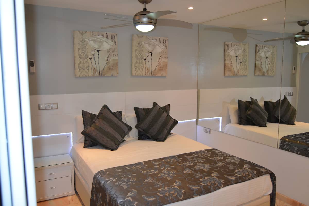 A bedroom with a large bed, two nightstands, a mirror, and wall art.