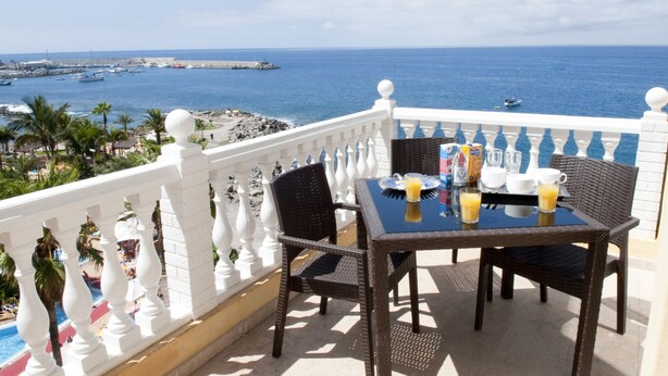 A balcony with a table set for breakfast, overlooking a marina and the sea. - Club Puerto Atlantico (Mogan)