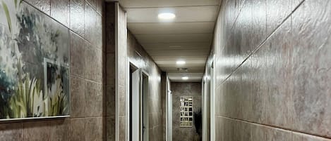 Un pasillo largo y estrecho con paredes y suelo de baldosas, que lleva a una escalera.