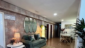 A modern living area with a green sofa, a small round table with a lamp, and a mirror on the wall. - Hostal Residencia Cardona (Arrecife)