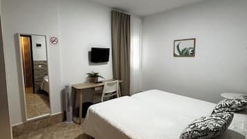 Una camera d'albergo con un letto, una scrivania, una sedia, un televisore e una piccola pianta.