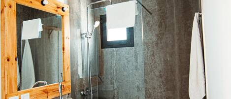 Une salle de bain avec un miroir encadré en bois, un lavabo blanc, une douche et une serviette accrochée au mur.