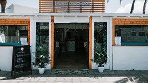Un restaurante frente al mar con fachada de madera, un letrero que dice 'Punta Elena Beach' y una pizarra con el menú en el exterior.