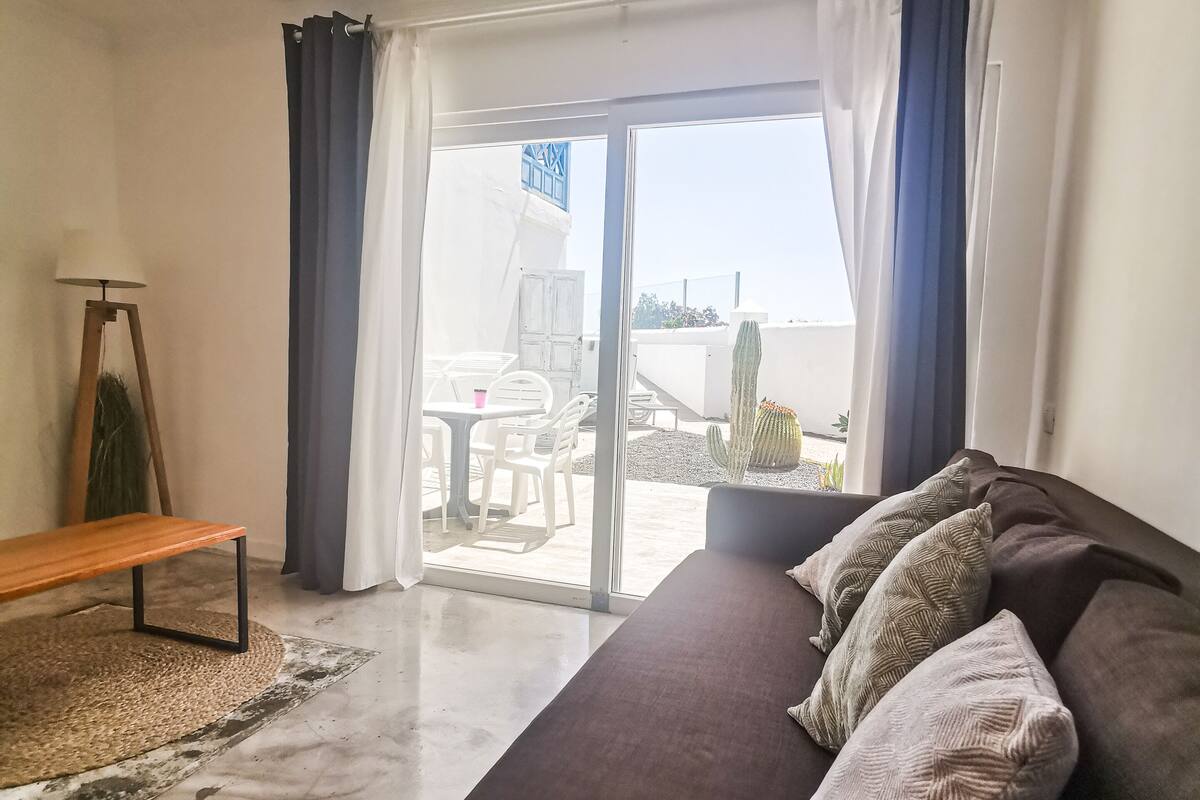 A modern bedroom with a large bed, a bench, and a view of the outside balcony.