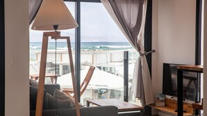Una sala de estar con vista al océano, un sofá, una lámpara y un televisor.