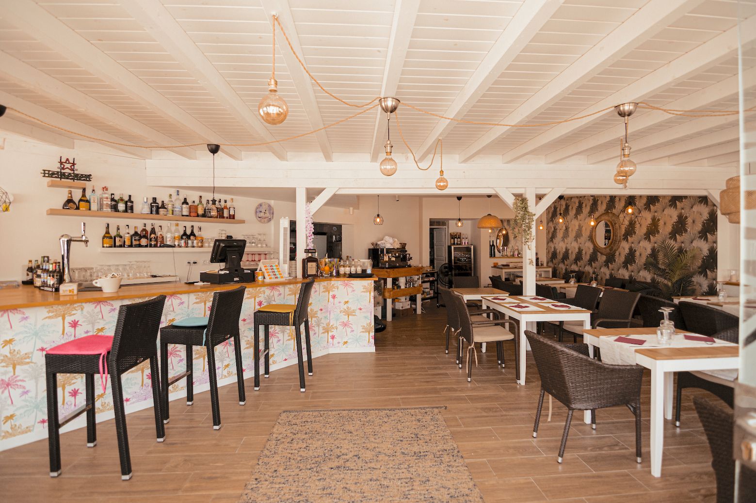 A restaurant with a bar area, wooden floors, and a patterned wall.