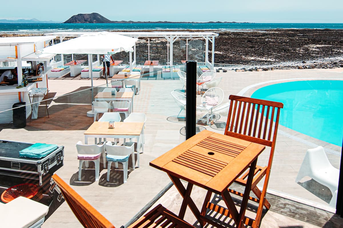 A poolside area with outdoor seating and a view of the sea.